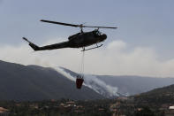 A Lebanese army helicopter takes off from a water storage point after it refilled a tank to extinguish a forest fire, at Qobayat village, in the northern Akkar province, Lebanon, Thursday, July 29, 2021. Lebanese firefighters are struggling for the second day to contain wildfires in the country's north that have spread across the border into Syria, civil defense officials in both countries said Thursday. (AP Photo/Hussein Malla)