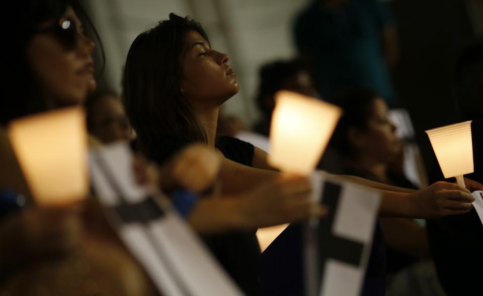 People hold candles as they attend a memorial by non-governmental organization (NGO) Rio de Paz (Rio of Peace), held in memory of police officers from the Police Peacekeeping Unit (UPP) who were killed while carrying out their duty, in downtown Rio de Janeiro March 17, 2014. The introduction of the peacekeeping program in the Rio de Janeiro slums is part of efforts to crack down on crime and increase security as the city prepares to host the 2014 World Cup soccer tournament and the 2016 Olympic Games. REUTERS/Sergio Moraes (BRAZIL - Tags: SOCIETY CIVIL UNREST CRIME LAW SPORT SOCCER WORLD CUP)