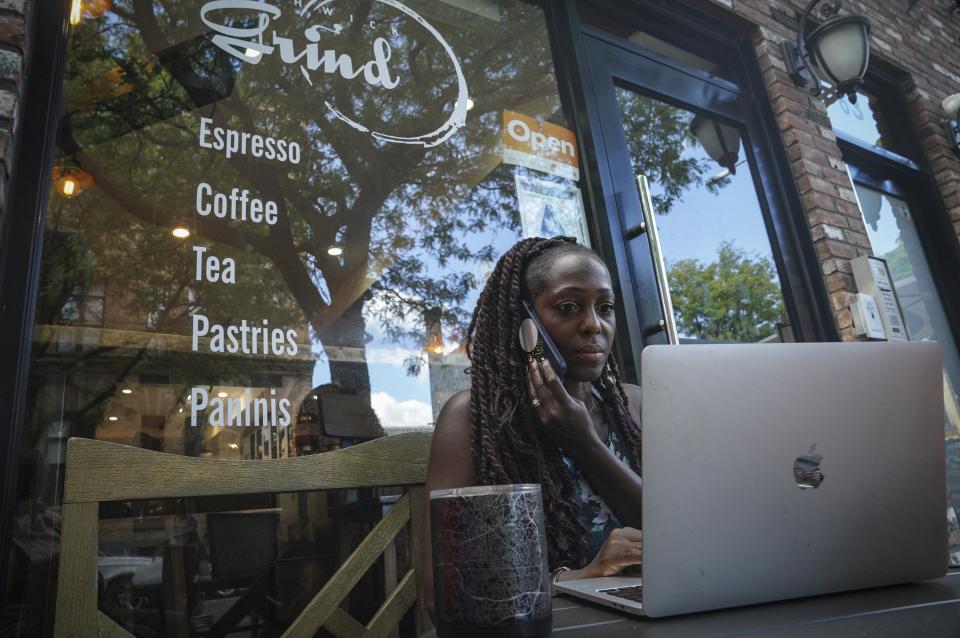 Kymme Williams-Davis sits outside Bushwick Grind Café she owns, as she juggles taking online orders and working behind the counter, Thursday Sept. 8, 2022, in New York. Williams-Davis said, with inflation, she hasn't seen costs going up and fluctuating this much since she opened her café in 2015. (AP Photo/Bebeto Matthews)
