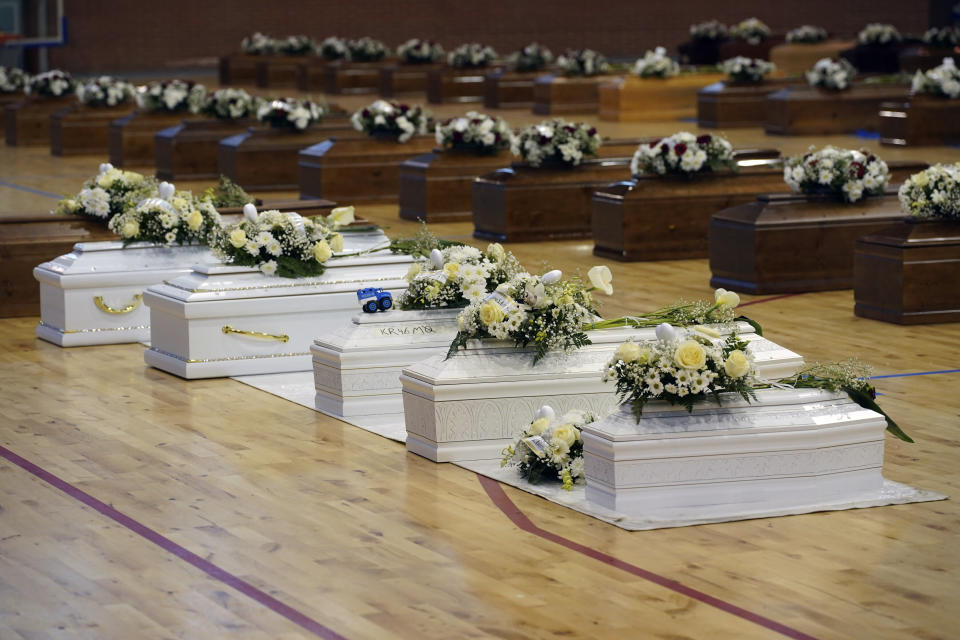 The coffins of the victims of last Sunday's shipwreck are lined up at the local sports hall in Crotone, southern Italy, Tuesday, Feb. 28, 2023. At least 65 people, including 14 minors, died when their overcrowded wooden boat slammed into shoals 100 meters (yards) off the shore of Cutro and broke apart early Sunday in rough seas. Eighty people survived, but many more are feared dead since survivors indicated the boat had carried about 170 people when it set off last week from Izmir, Turkey. (Antonino D'Urso/LaPresse via AP)