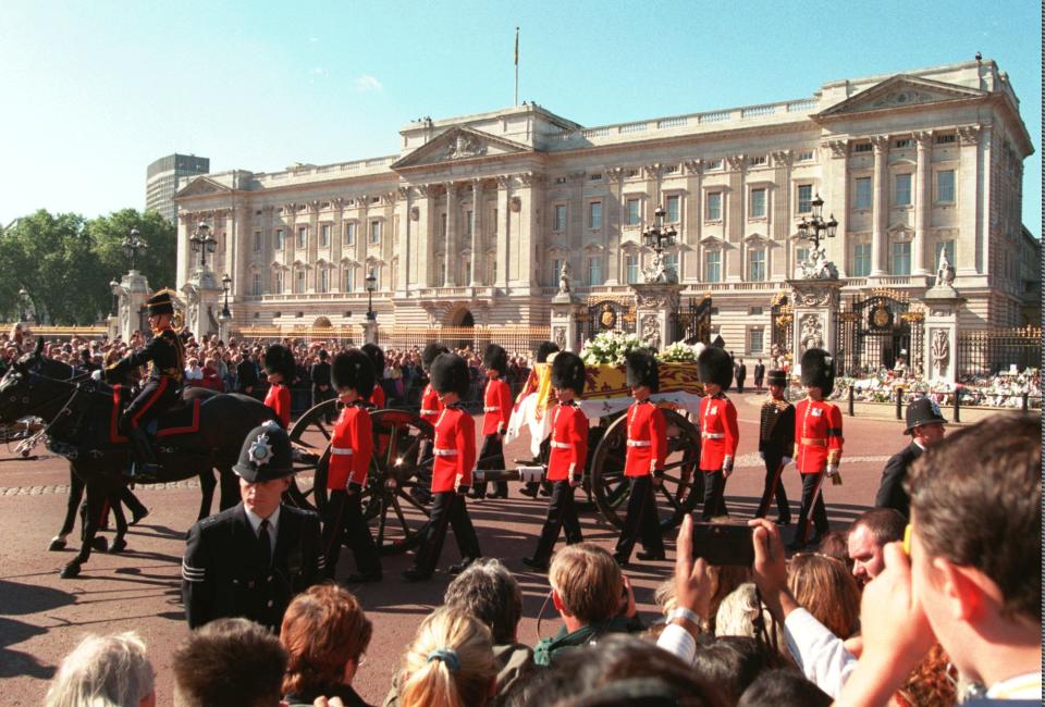 The casket containing the body of Diana, Princess of Wales, is escorted by Welsh Guardsmen and soldiers of the Royal Horse Artillery, as it is borne on a gun carriage past Buckingham Palace, during the funeral procession in Londay, Saturday Aug. 6, 1997. (AP Photo/Adrian Dennis)