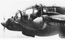 The forward machine gunner is seen sitting at his battle position in the nose of a German Heinkel He 111 bomber plane, while en route to England in November 1940.