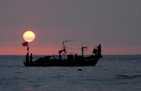 In this Thursday, Aug. 30, 2018 file photo, Lebanese fishermen sit at the bow of a fishing boat, in the Mediterranean Sea as the sun sets, at Ramlet al-Baida public beach, in Beirut, Lebanon. (AP Photo/Hussein Malla, File)