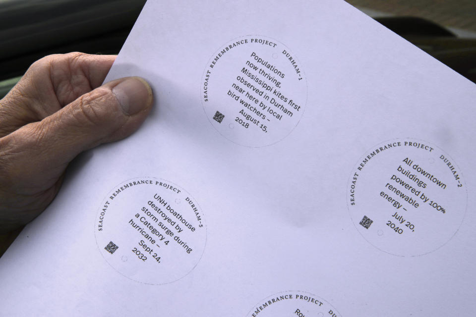 Artist Thomas Starr holds sign printouts, part of a public design installation, on the banks of the Oyster River in Durham, N.H., Wednesday, Oct. 16, 2019. Starr, a graphic and information design professor from Boston's Northeastern University, created the project to address possible effects of climate change. (AP Photo/Charles Krupa)