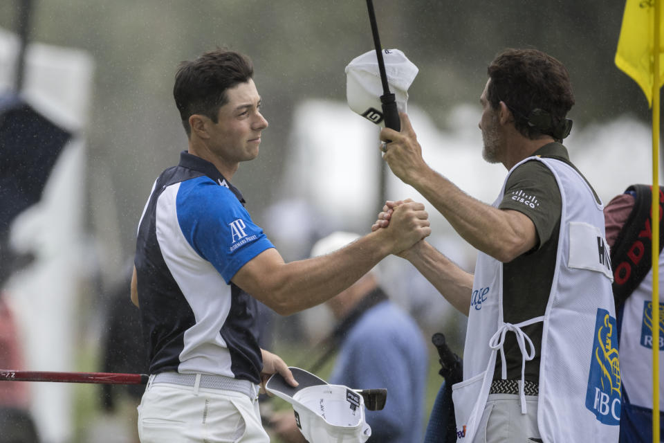 Viktor Holland, left, of Norway, shakes hands with his caddie on the ninth green during the first round of the RBC Heritage golf tournament, Thursday, April 13, 2023, in Hilton Head Island, S.C. (AP Photo/Stephen B. Morton)