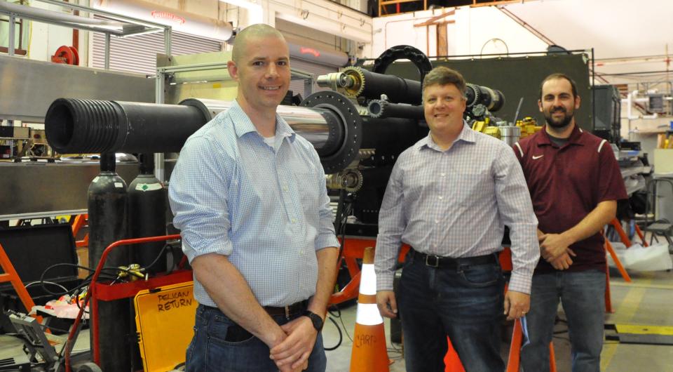 Naval Surface Warfare Center Dahlgren engineers (from left) Matthew Buckler, Gregory Fish and Thomas Houck stand in front of the new 105mm Gun Aircraft Unit they helped develop for the AC-130 gunship.