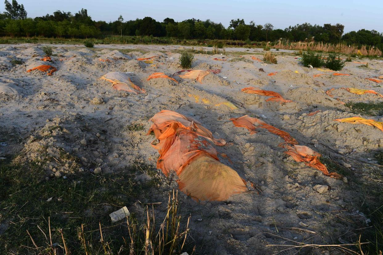 <p>Bodies of suspected Covid-19  victims are seen partially buried in the sand near a cremation ground on the banks of the Ganges</p> (AFP via Getty Images)