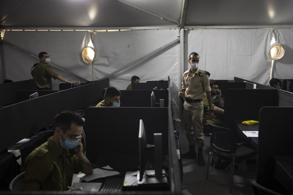 Israeli soldiers interview people infected with coronavirus to identify who they have been in contact with, at the headquarters of the Home Front Command, in Ramle, Central Israel, Tuesday, Aug. 25, 2020. As Israel struggles to control a coronavirus outbreak, it is calling in the army to help. At the instruction of the country's coronavirus czar, the military has set up a new "task force” that is playing a leading role in contact tracing and breaking the chain of infections. (AP Photo/Sebastian Scheiner)