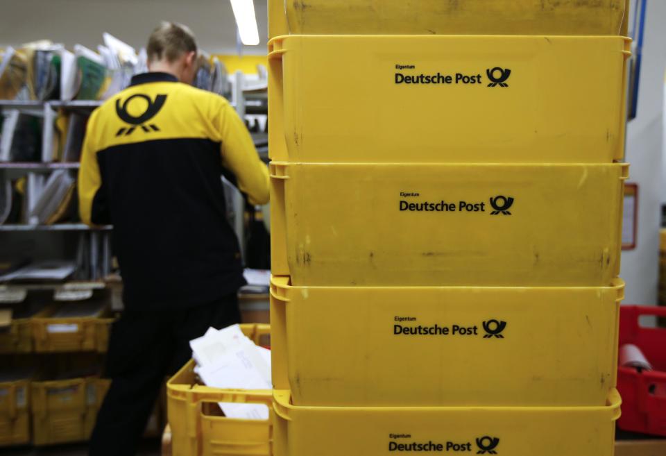 Transport boxes are pictured next to a Deutsche Post postman in Berlin