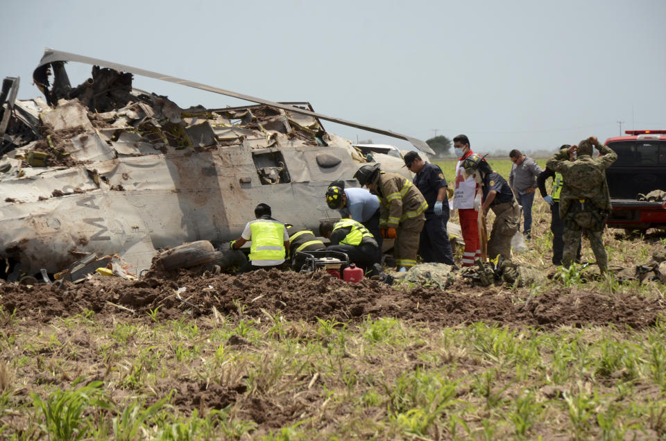 Emergency personnel work next to a navy Blackhawk helicopter crashed after supporting those who conducted the capture of drug lord Rafael Caro Quintero, near Los Mochis, Sinaloa state, Mexico, Friday, July 15, 2022. Mexico's navy said multiple people aboard died. (AP Photo/Guillermo Juarez)