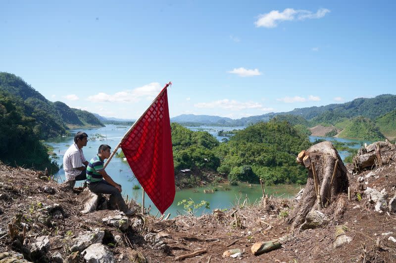 People hold a flag while sitting on the top of a mountain, in the hope of attracting military helicopters delivering aid to villages affected by Hurricanes Eta and Iota, in Alta Verapaz