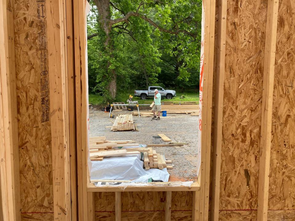 A worker with Eight Days of Hope surveys lumber options for the construction of the shelter.