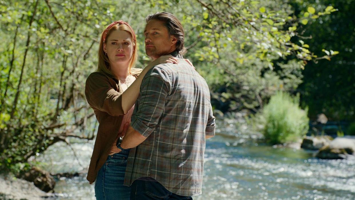 a man and woman posing for a picture next to a river