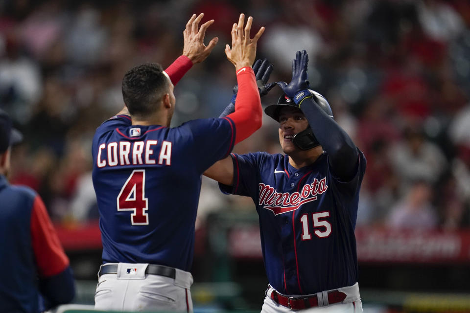 Minnesota Twins' Gio Urshela (15) celebrates with Carlos Correa (4) after hitting a home run during the sixth inning of a baseball game against the Los Angeles Angels in Anaheim, Calif., Friday, Aug. 12, 2022. (AP Photo/Ashley Landis)