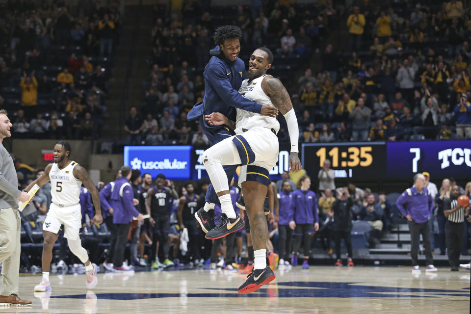 West Virginia guard Josiah Davis, left, and forward Jimmy Bell Jr., right, celebrate after a score against TCU during the first half of an NCAA college basketball game Wednesday, Jan. 18, 2023, in Morgantown, W.Va. (AP Photo/Kathleen Batten)