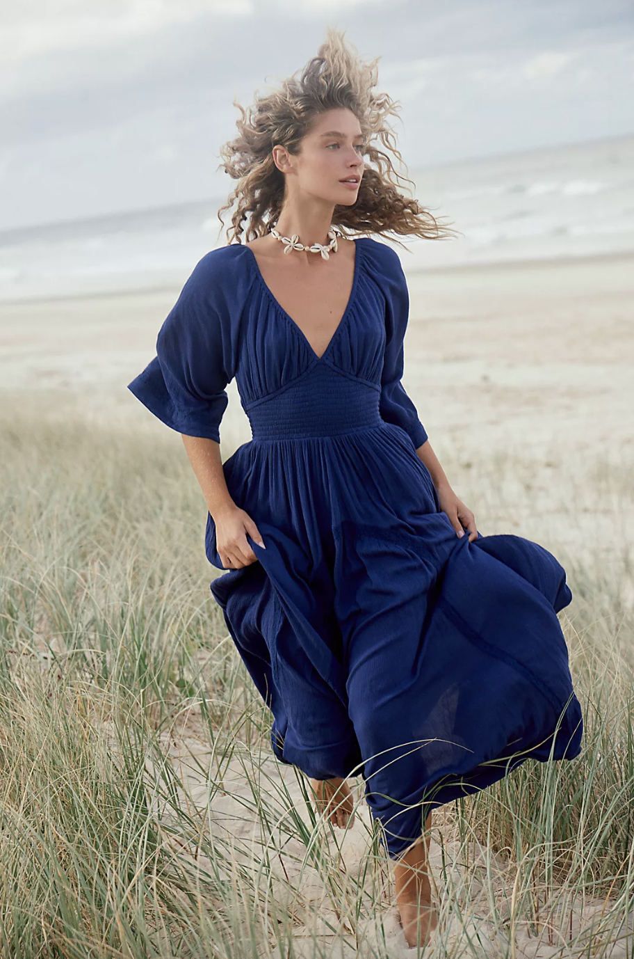 model with curly blonde hair running in navy blue Dixie Maxi dress (photo via Free People)