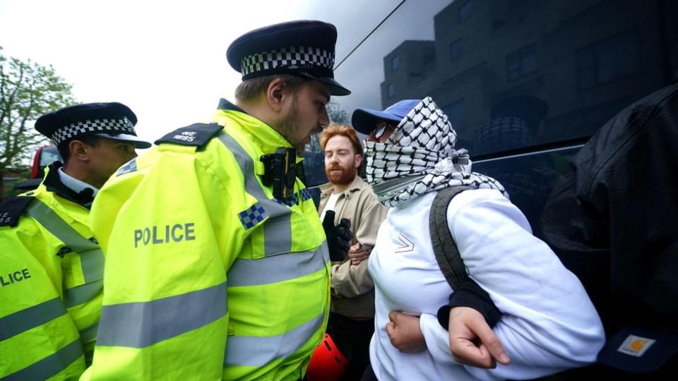 A police officer speaking to a protester next to the coach