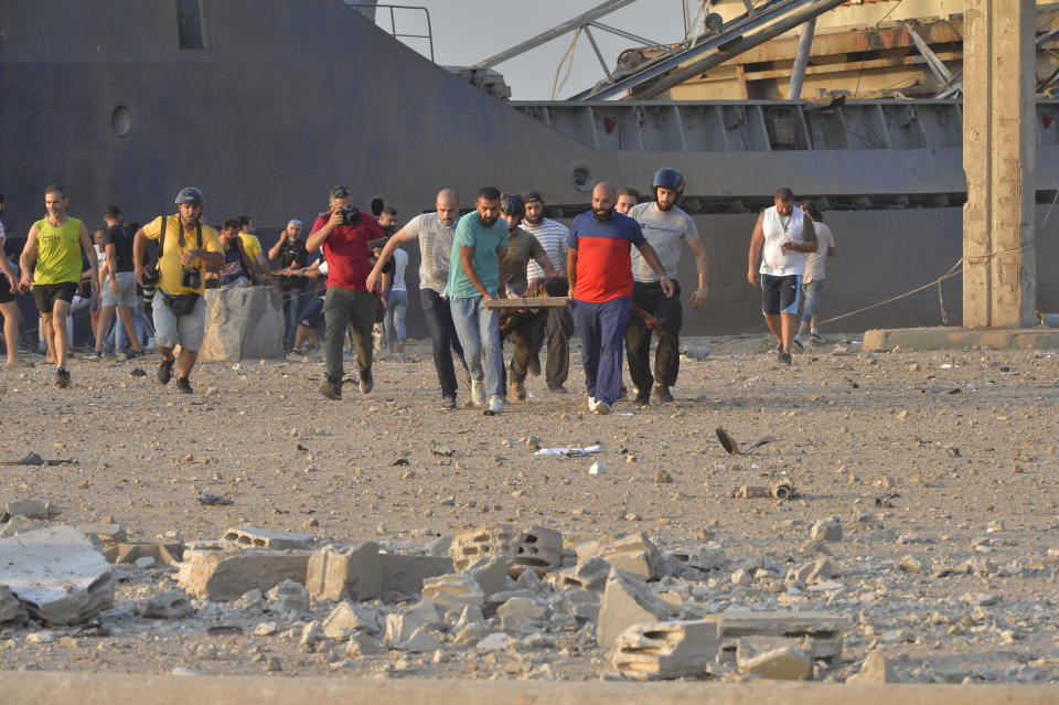 People carry wounded people away from the site after a fire at a warehouse with explosives at the Port of Beirut led to massive blasts in Beirut, Lebanon on August 4, 2020. A large number of people were reportedly injured in the blasts, while former Prime Minister Saad al-Hariri -- who lives near the area of the explosions -- is said to be unharmed, according to initial reports. (Photo by Houssam Shbaro/Anadolu Agency via Getty Images)