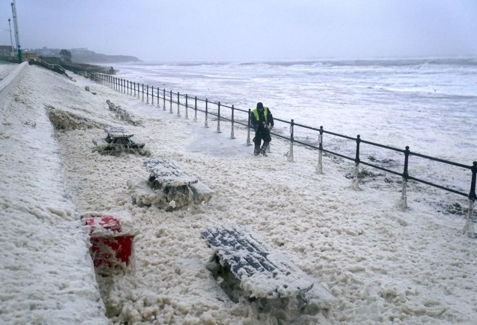 A man walks through sea foam in Seaburn, Sunderland,  as Storm Babet batters the country (PA)