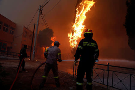 Firefighters and soldiers try to extinguish a wildfire burning in the town of Rafina, near Athens, Greece, July 23, 2018. REUTERS/Costas Baltas