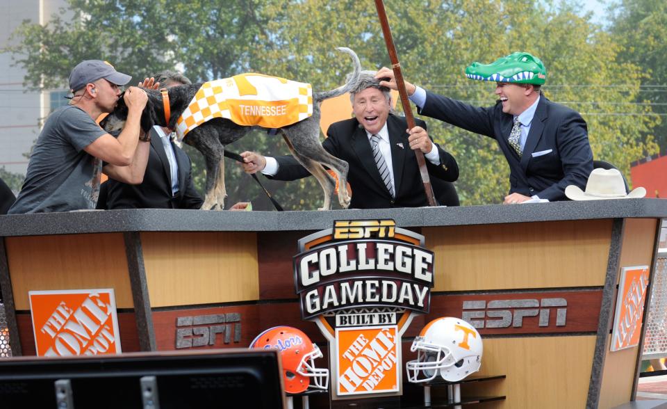 Country music singer Kenny Chesney kisses UT football mascot "Smokey" with analysts Lee Corso, center, and Kirk Herbstreit as they pick the game winner on ESPN College GameDay from Circle Park on the University of Tennessee campus on Sept. 15, 2012. Chesney appeared as the guest game picker of the week.