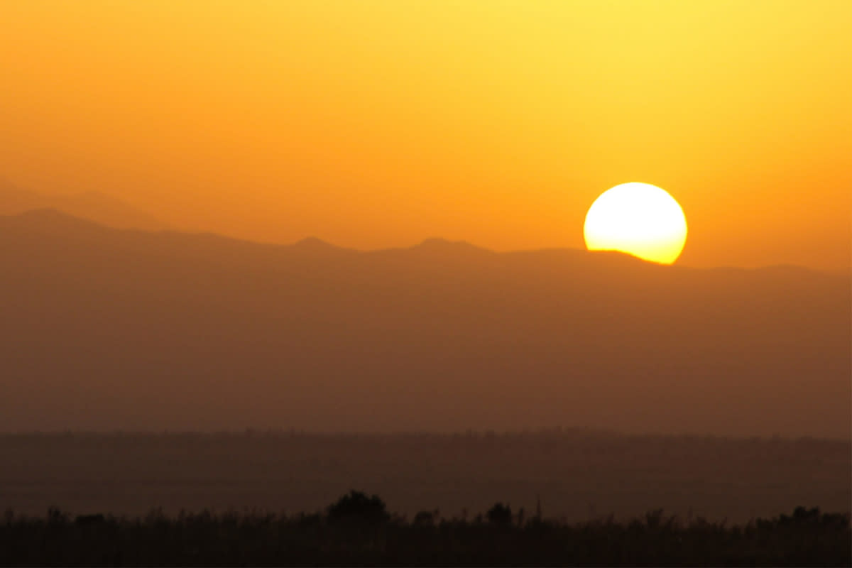 The sun rises over the mountains. In the Pacific Northwest, a heat dome has led to record-breaking temperatures.