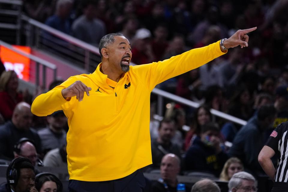 Michigan basketball coach Juwan Howard points as he directs his players on the court.