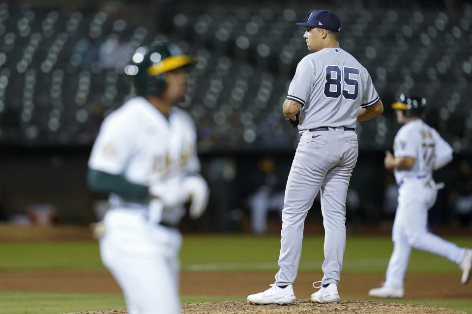 New York Yankees relief pitcher Greg Weissert (85) looks toward home plate after walking Oakland Athletics' Tony Kemp, foreground, to load the bases during the seventh inning of a baseball game in Oakland, Calif., Thursday, Aug. 25, 2022. (AP Photo/Godofredo A. Vásquez)