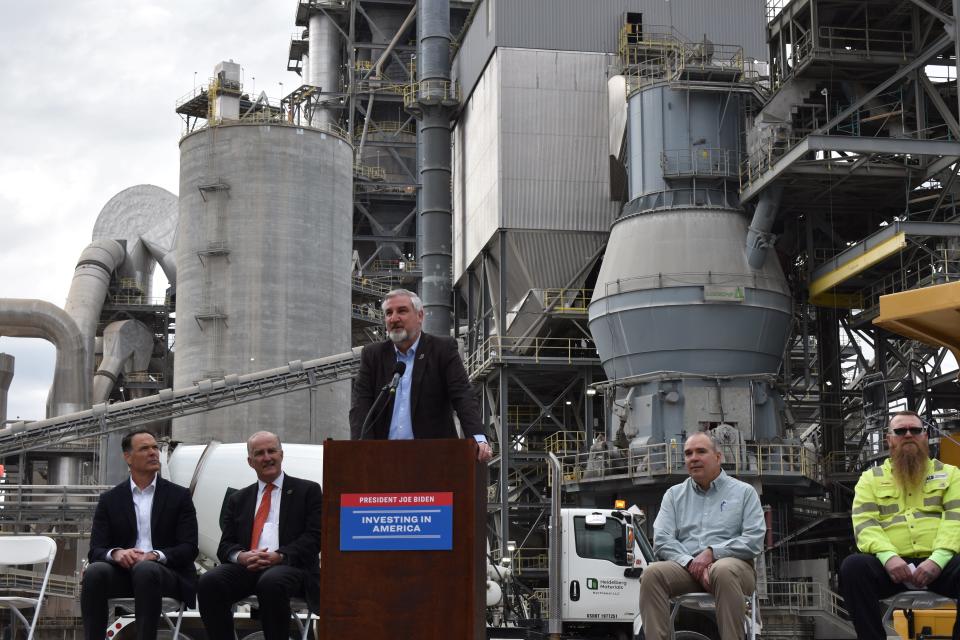 Gov. Eric Holcomb talks about a Department of Energy investment in a carbon capture, transport and storage project at the Heidelberg Materials plant in Mitchell on Monday. Seated from left are Chris Ward, Heidelberg Materials North America CEO; David Crane, U.S. Department of Energy under secretary; Tracy Crowther, Heidelberg Materials plant manager; and Doug Duncan, president of United Steelworkers Local 7-00030.