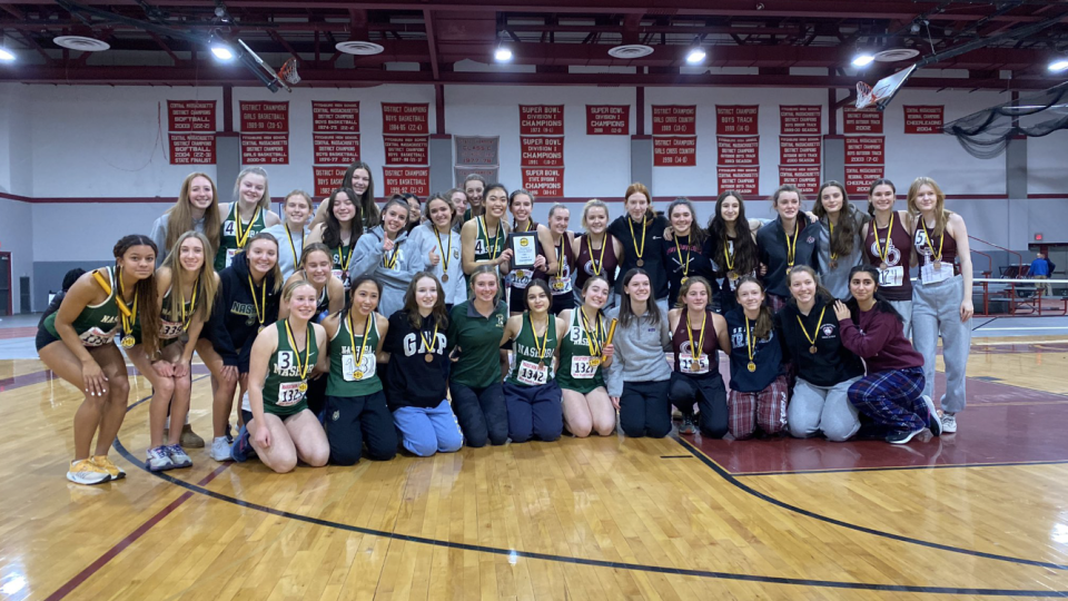 The Nashoba girls indoor track team celebrates winning the Mid-Wach B league meet.