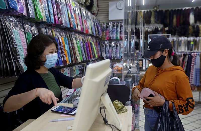 Pan Emi, wife of Gan Xianbing, interacts with a client at her store in Guadalajara