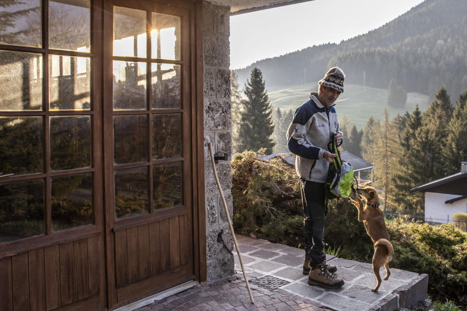 In this image taken on Thursday, April 23, 2020, alpine guide Ernesto Cocchetti, 57, prepares to go walking outside his house in Castione Della Presolana, near Bergamo, northern Italy. Cocchetti predicts a return to "living with nature's rhythms" once government restrictions to prevent the spread of COVID-19 will be eased. (AP Photo/Luca Bruno)