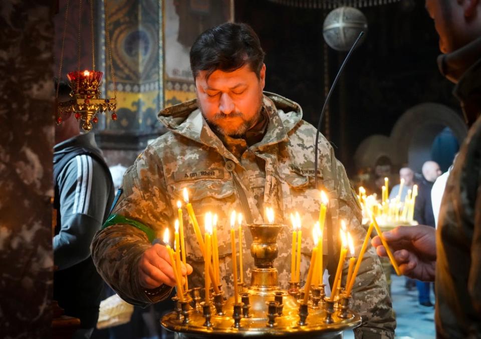 A Ukrainian soldier lights candles at the Volodymysky Cathedral during Easter celebration in Kyiv (AP)