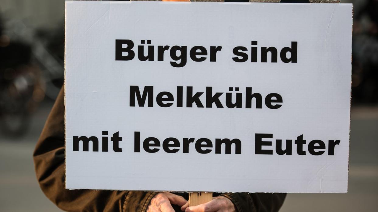 Ein Bürger demonstriert mit einem Plakat mit der Aufschrift «Bürger sind Melkkühe mit leerem Euter» gegen Abgabenlast. Foto: Andreas Arnold