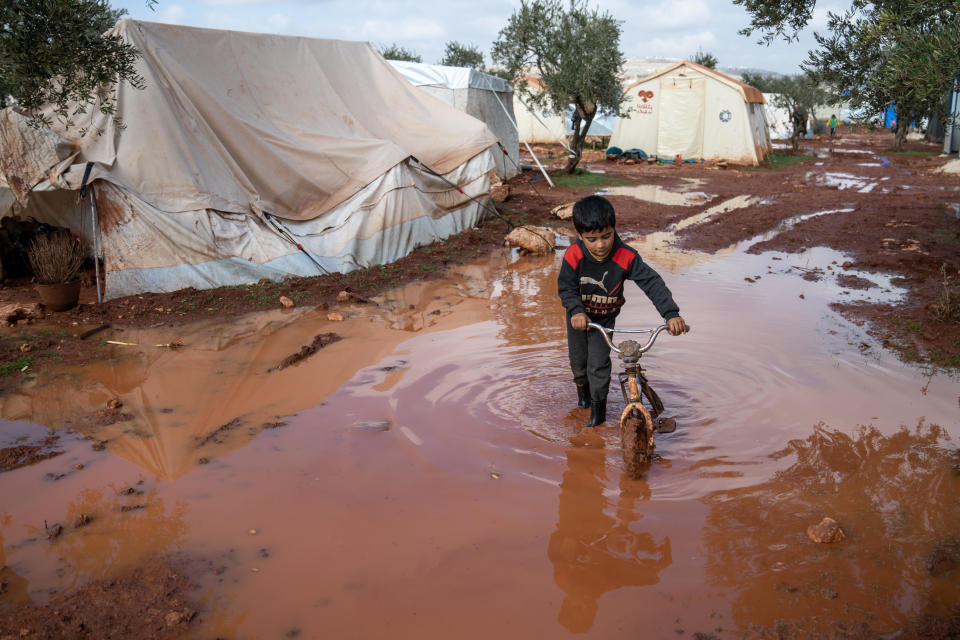 A Syrian young boy pulls his bicycle in muddy water in Zaitoun refugee camp after a heavy rainstorm led to a flood in Syrian refugee camps in Idlib on January 19, 2021. / Credit: NurPhoto