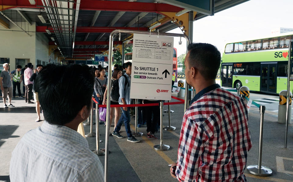 Two men reading one of the signs put up to inform commuters of the shuttle bus services available on Sunday (10 December). (PHOTO: Dhany Osman / Yahoo News Singapore)