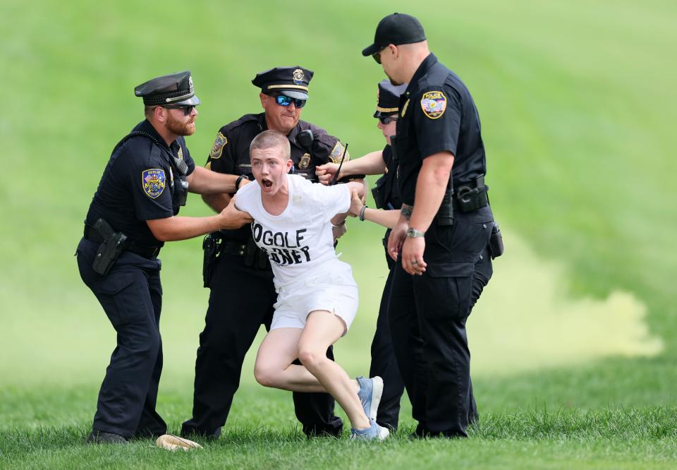 Climate change protestors are ushered off the 18th green by police officers during the final round of the Travelers Championship at TPC River Highlands on June 23, 2024 in Cromwell, Connecticut.