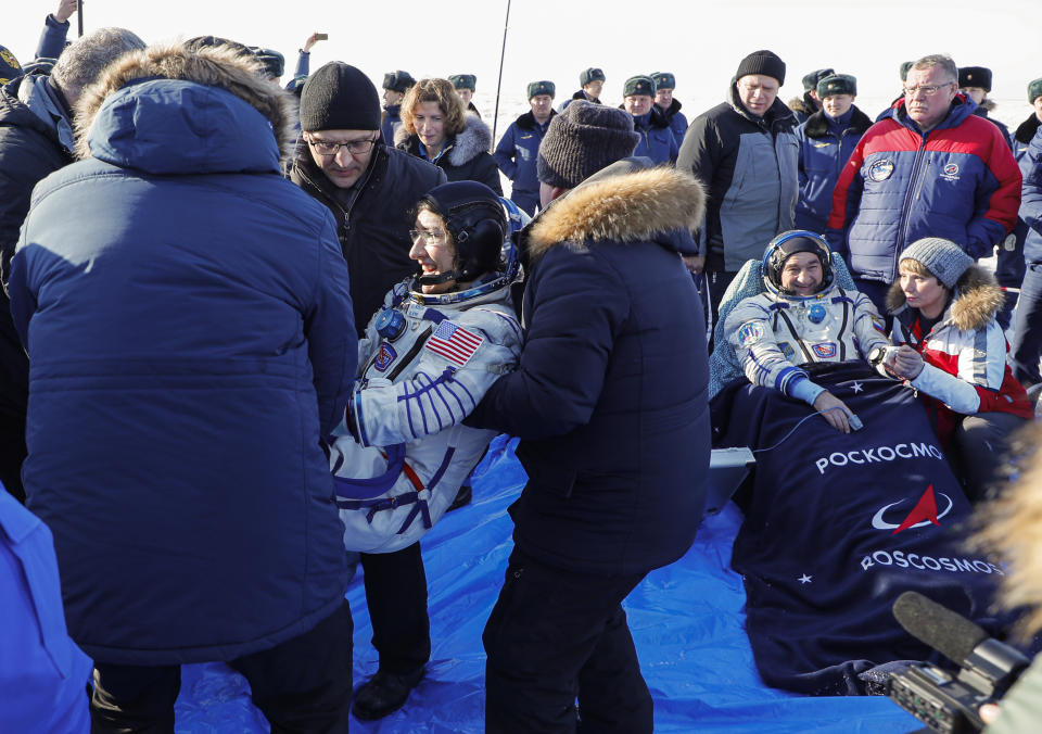 Russian search and rescue team members carry U.S. astronaut Christina Koch, left, as Russian cosmonaut Alexander Skvortsov of Roscosmos rests shortly after the landing of the Russian Soyuz MS-13 space capsule about 150 km ( 80 miles) south-east of the Kazakh town of Zhezkazgan, Kazakhstan, Thursday, Feb. 6, 2020. A Soyuz space capsule with U.S. astronaut Christina Koch, Italian astronaut Luca Parmitano and Russian cosmonaut Alexander Skvortsov, returning from a mission to the International Space Station landed safely on Thursday on the steppes of Kazakhstan. Koch wrapped up a 328-day mission on her first flight into space, providing researchers the opportunity to observe effects of long-duration spaceflight on a woman as the agency plans to return to the Moon under the Artemis program. (Sergei Ilnitsky/Pool Photo via AP)