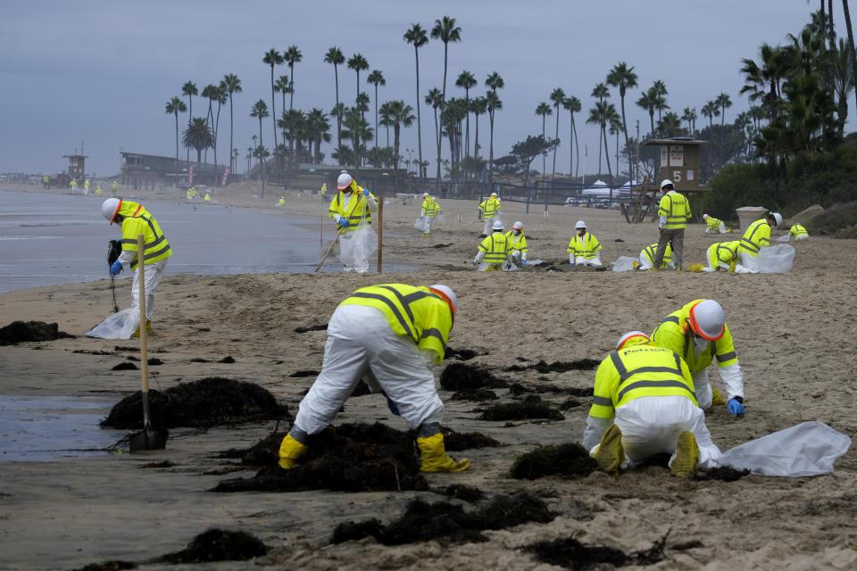 FILE - In this Oct. 7, 2021, file photo, workers in protective suits clean the contaminated beach in Corona Del Mar after an oil spill in Newport Beach, Calif. A group of environmental organizations is demanding the Biden administration suspend and cancel oil and gas leases in federal waters off the California coast after a recent crude oil spill. The Center for Biological Diversity and about three dozen organizations sent a petition Wednesday, Oct. 20, 2021, to the Department of the Interior, arguing it has the authority to end these leases. (AP Photo/Ringo H.W. Chiu, File)