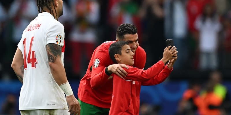 Ein Knirps rennt aufs Feld und sichert sich ein Selfie mit Portugal-Megastar Cristiano Ronaldo<span class="copyright">AFP via Getty Images</span>