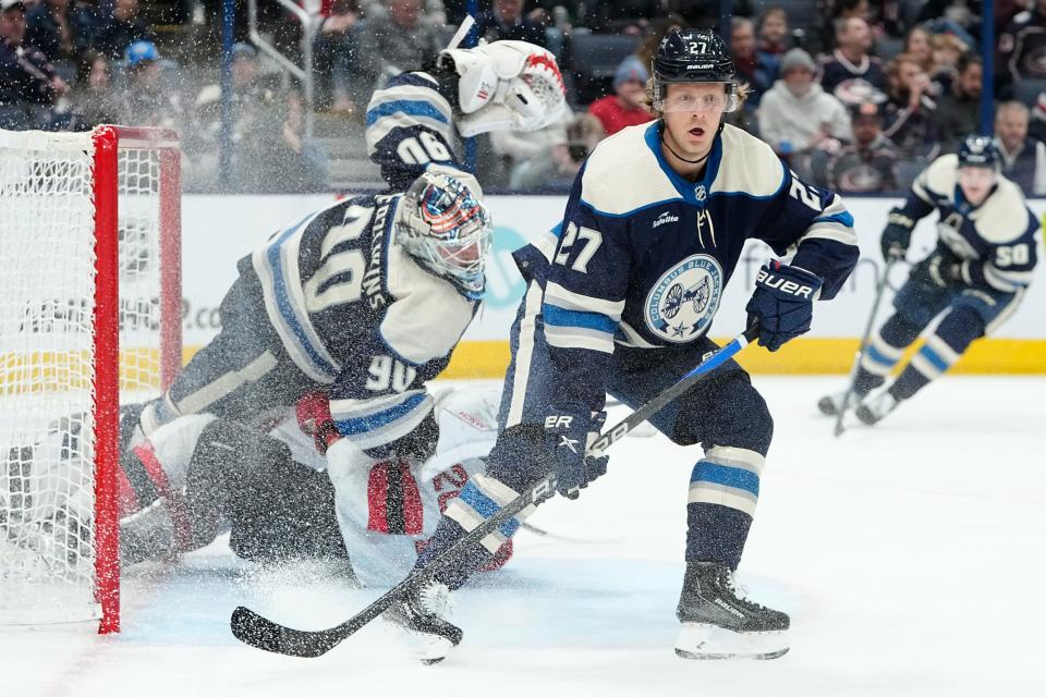 Feb 14, 2023; Columbus, Ohio, USA;  Columbus Blue Jackets defenseman Adam Boqvist (27) stands in front of goaltender Elvis Merzlikins (90) as he’s plowed into by New Jersey Devils center Michael McLeod (20) during the second period of the NHL hockey game at Nationwide Arena. Mandatory Credit: Adam Cairns-The Columbus Dispatch