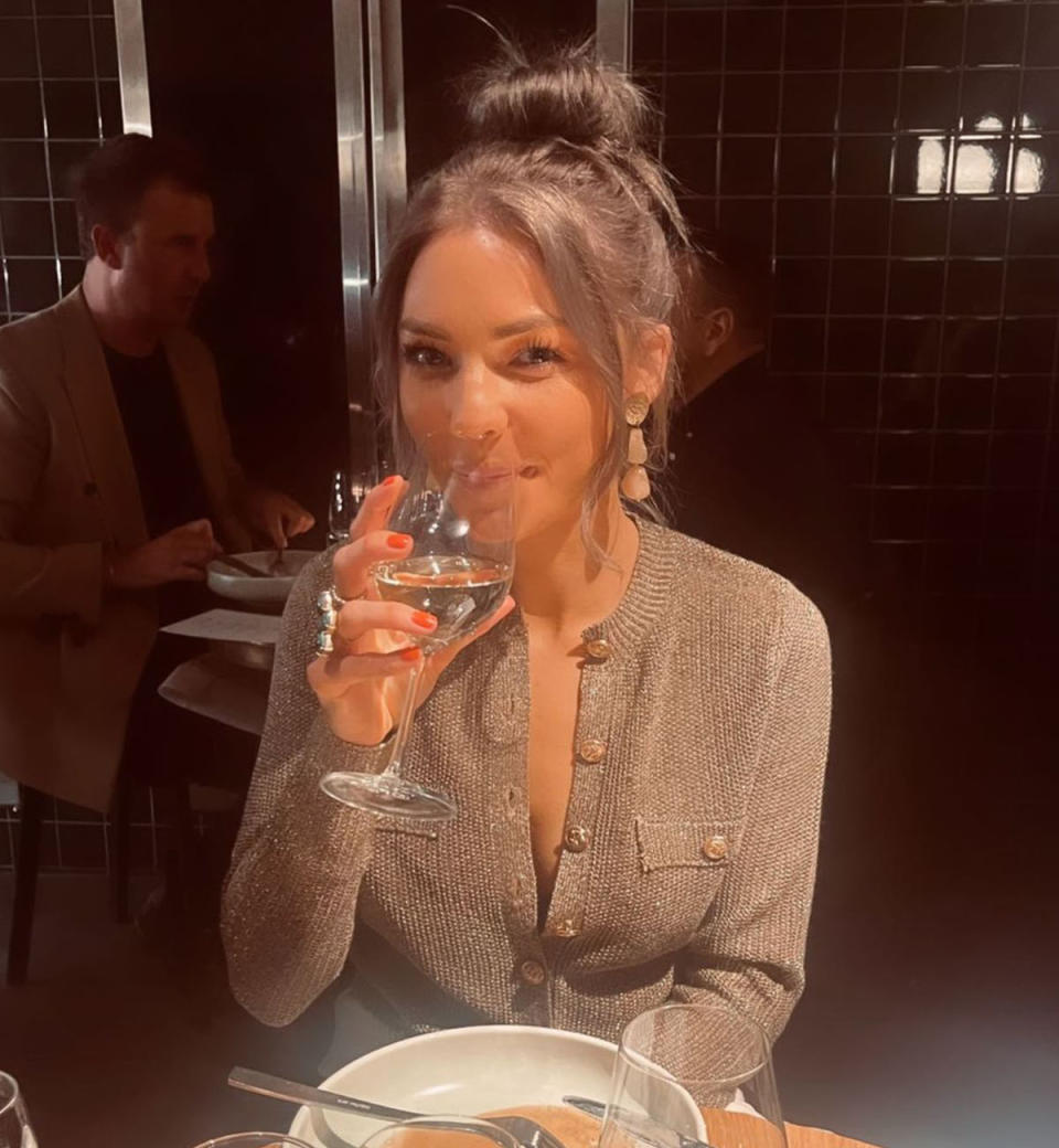 Sam Frost poses with a glass of wine showing off her new brunette hairdo