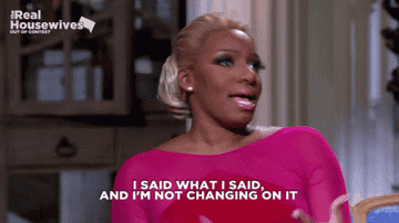 Nene Leakes smiles while gesturing passionately, wearing a stylish off-the-shoulder dress. Text on image: "I said what I said, and I'm not changing on it."