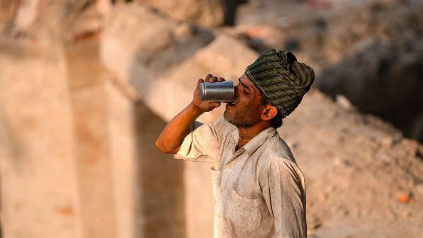 A construction worker quenches his thirst while taking a break, amid the ongoing intense heat wave on a hot summer day along the bank of the Yamuna River, in New Delhi.