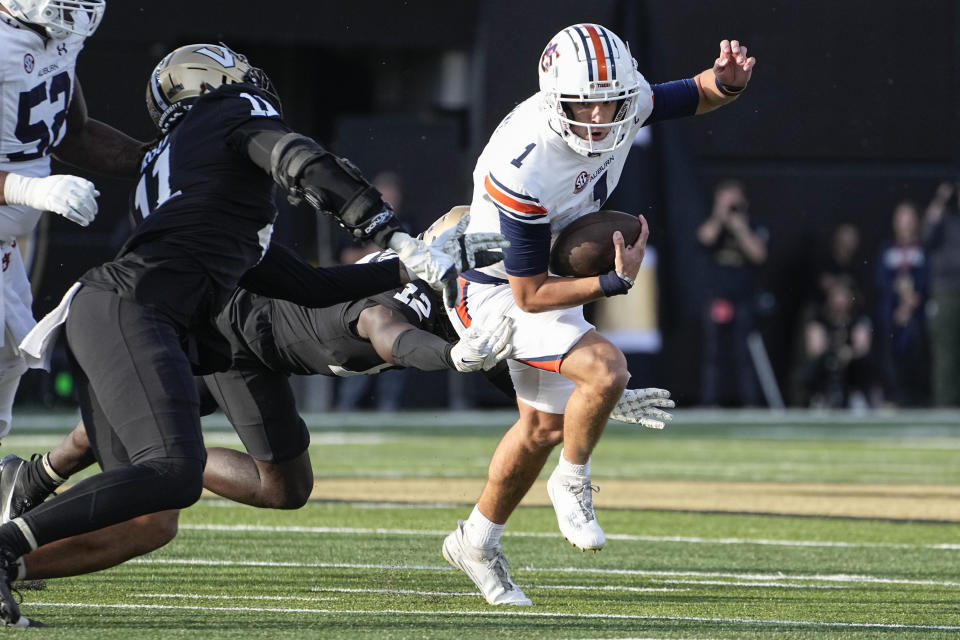 Auburn quarterback Payton Thorne (1) runs past Vanderbilt defensive end Darren Agu, left, and linebacker Jeffrey Ugochukwu (12) in the first half of an NCAA college football game Saturday, Nov. 4, 2023, in Nashville, Tenn. (AP Photo/George Walker IV)