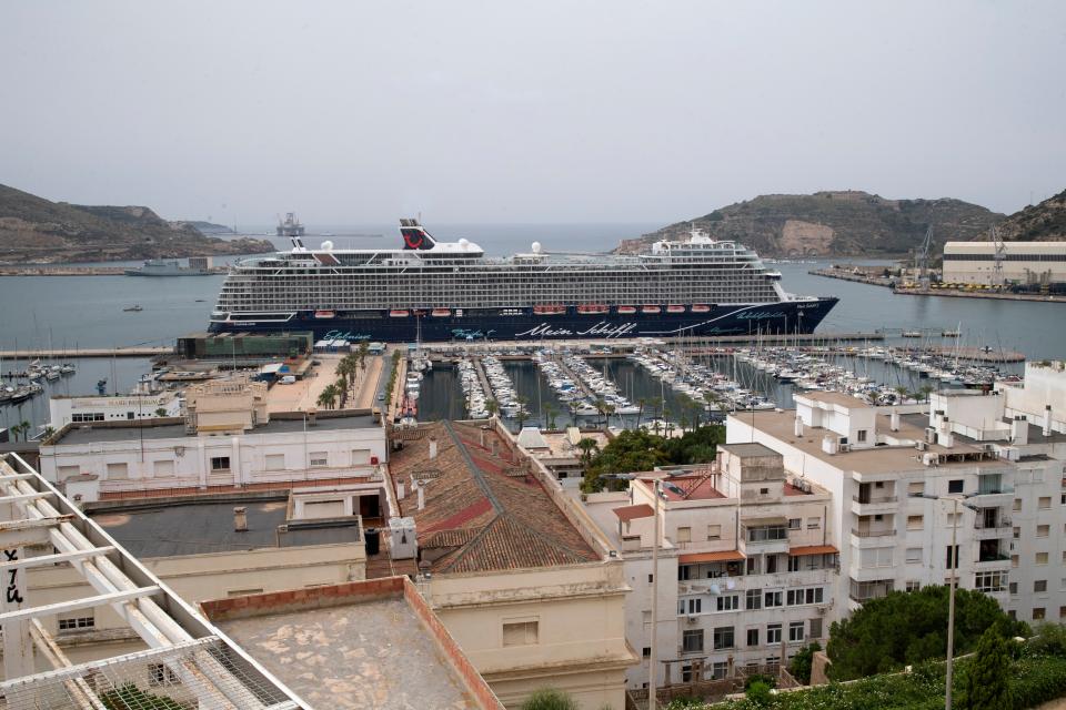 This image shows the tops of buildings in front of a cruise ship docked in Spain.