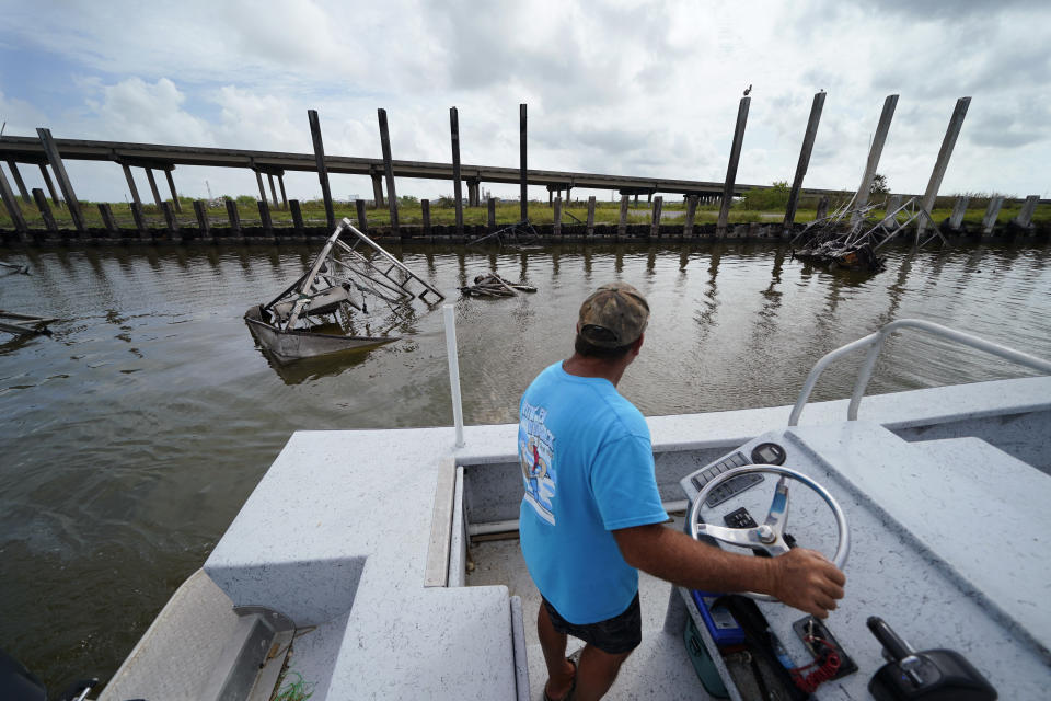 Frank Jurisich motors past shrimp boats that caught fire and burned during Hurricane Ida, as he and his brother go check on their oyster beds in Plaquemines Parish, La., Monday, Sept. 13, 2021. Ida's heavy rains caused freshwater and sediment to flood coastal estuaries, killing the shellfish, Jurisich said. (AP Photo/Gerald Herbert)