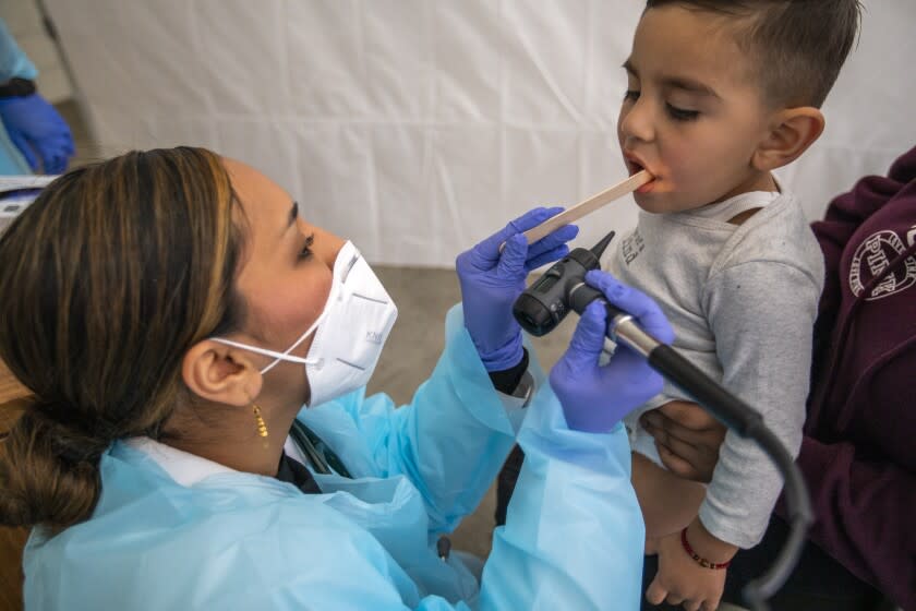 LOS ANGELES, CA - JANUARY 27: (Editor's note: This photo is initially for a Hayley Smith story.) Dr. Faraiba Faqeerzada PA-C (FP), left, examines two year Benjamin Salazar at South Central Family Health Center on Thursday, Jan. 27, 2022 in Los Angeles, CA. The center is located in a neighborhood with the highest Omicron case rates in the county. Benjamin has been having an upset stomack the last few days and his mother brought him in to get checked out. (Francine Orr / Los Angeles Times)