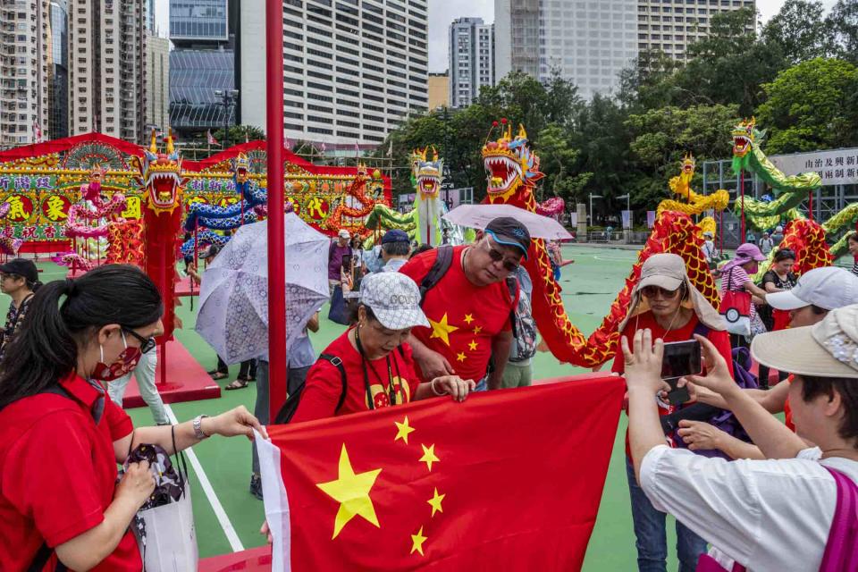 2023年6月30日，維園「慶祝香港回歸祖國二十六週年」慶祝活動，現場有本地特色大型花牌配合26條傳統舞龍，市民帶同國旗拍照。攝：林振東/端傳媒