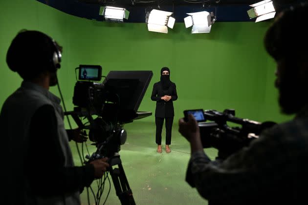 In this photograph taken on May 28, 2022, an Afghan female presenter with news network 1TV, Lima Spesaly (C) with her face covered by a veil, speaks during a live broadcast at the 1TV channel station in Kabul. - After initially defying the Taliban order to cover their faces on air, Afghan women television presenters are broadcasting news and other programmes wearing masks. Spesaly, said it was difficult to work like this for hours but vowed to fight for her rights and of other Afghan women that are being increasingly crushed by the hardline Islamist rulers. (Photo: Photo by WAKIL KOHSAR/AFP via Getty Images)